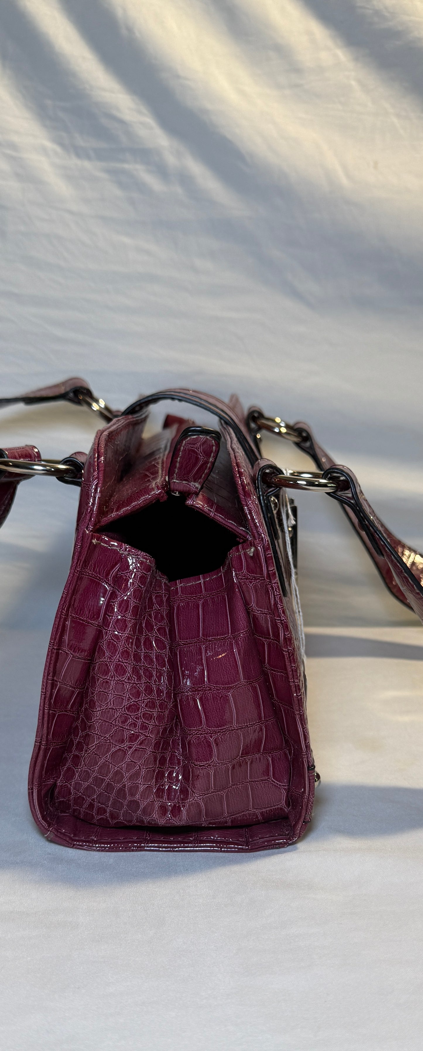 Pre-owned. Crocodile-embossed burgundy patent leather shoulder bag with silver-tone hardware and zipper closure.