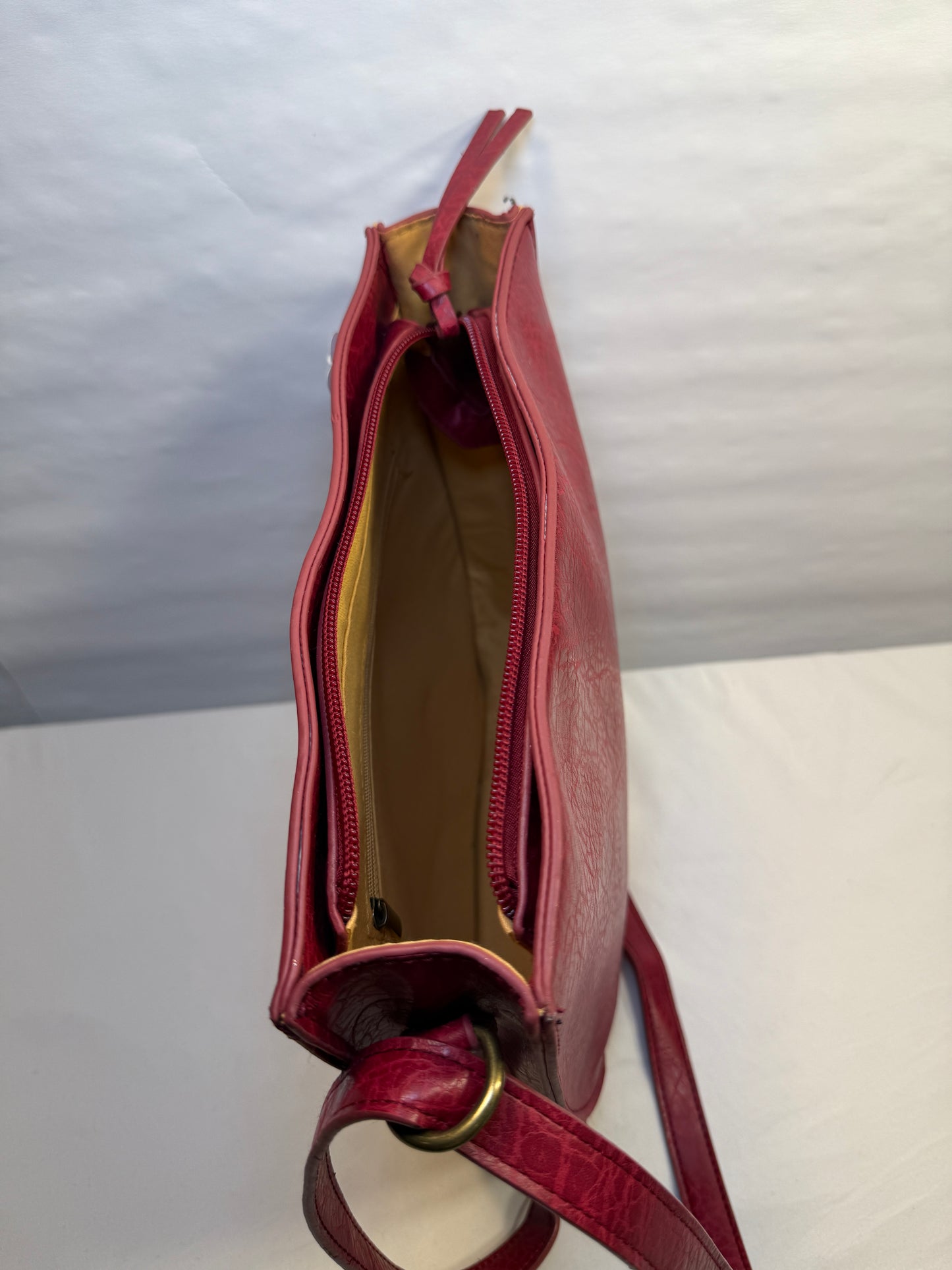 Crossbody Red Faux leather bag w/adjustable strap and side pocket.